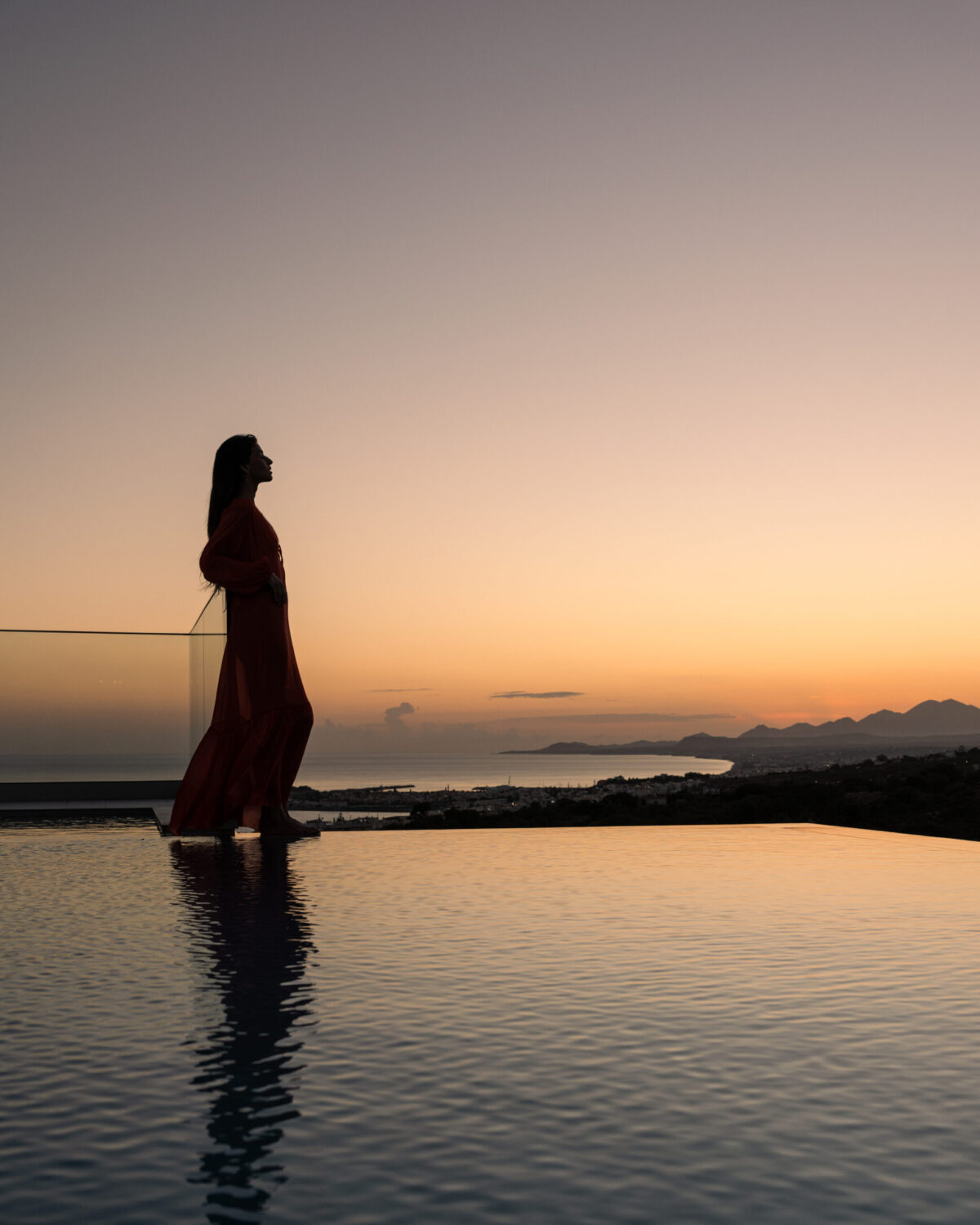 A WOMAN NEAR THE POOL DURING THE SUNSET AT AERIAL VILLA